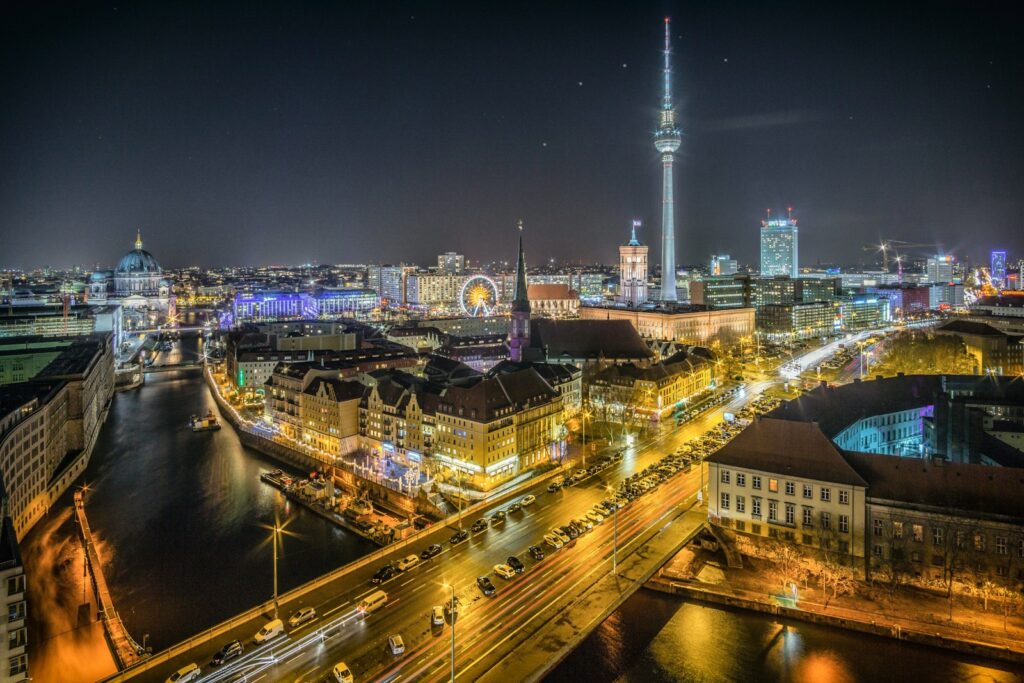 Berlin - time-lapse photography of vehicle at the road in between the building at nighttime aerial photography